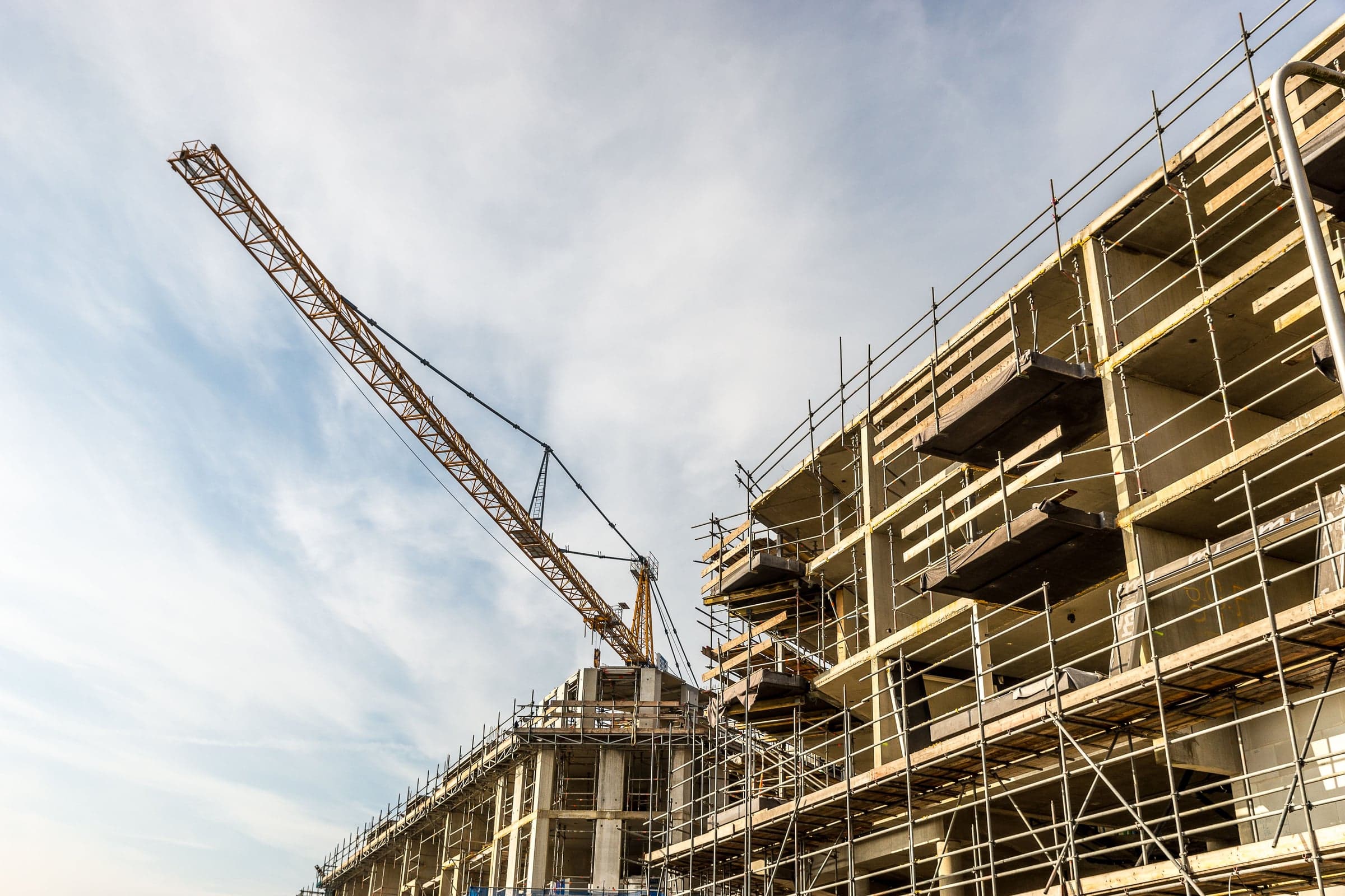 Turmdrehkran über einem Rohbau mit Betonskelett und Gerüst